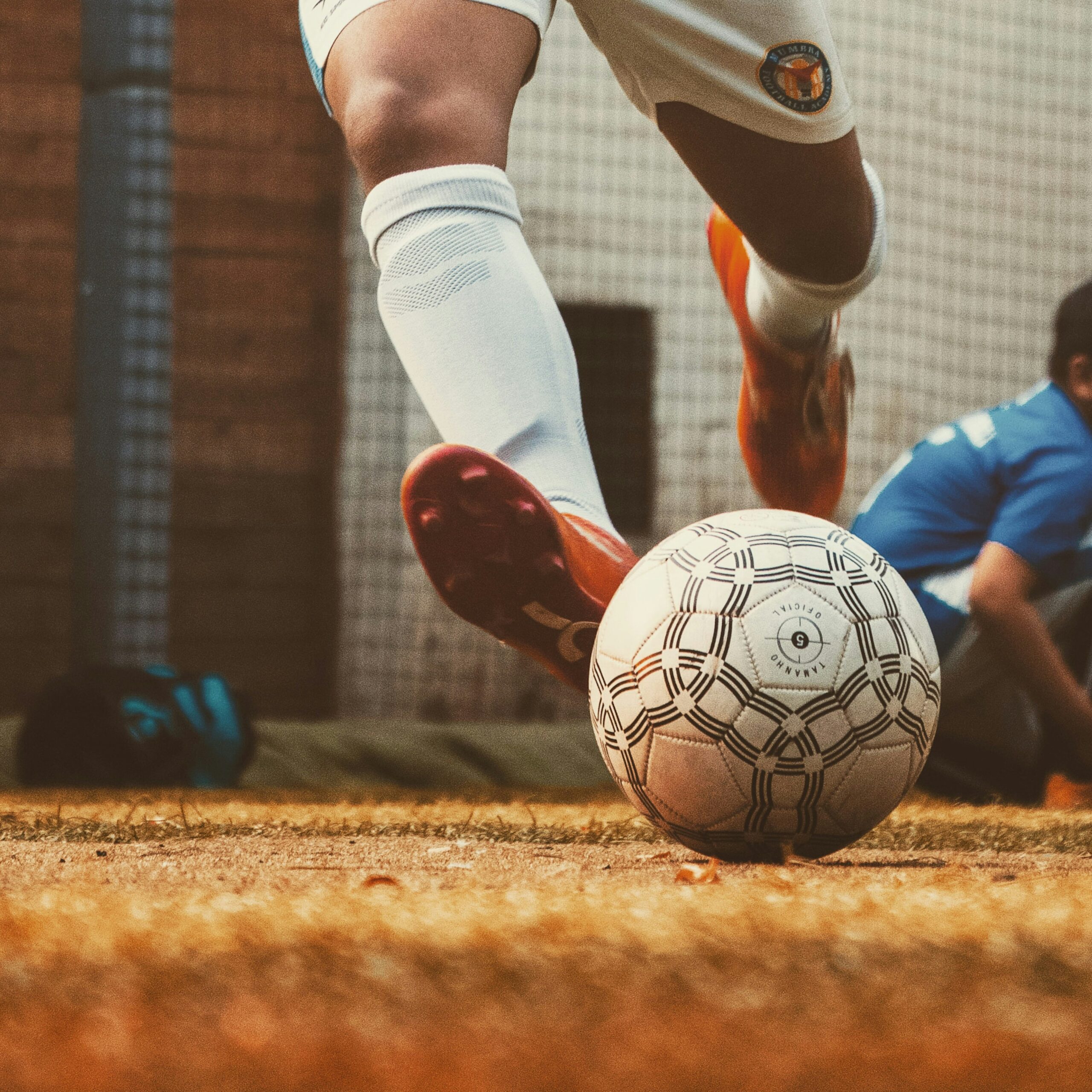 Player striking a ball on a worn pitch
